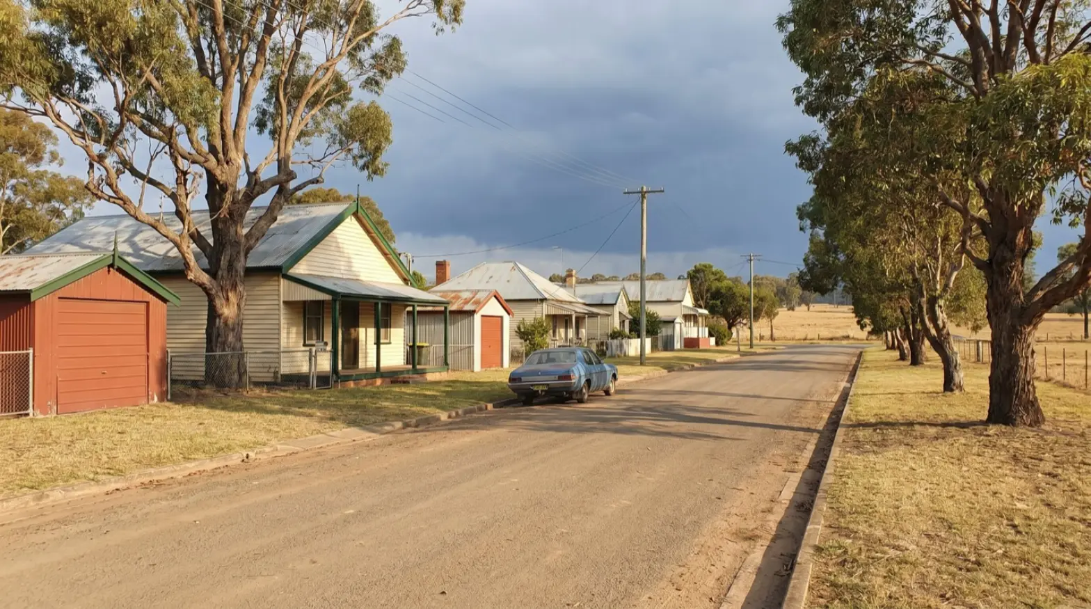 A quiet Bellbird street of weatherboard miners' cottages with a red garage at the corner
