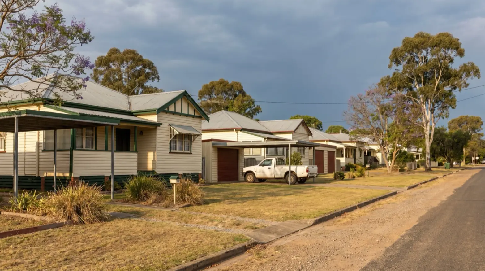 An older Kurri Kurri street with weatherboard houses, carports and red roller doors
